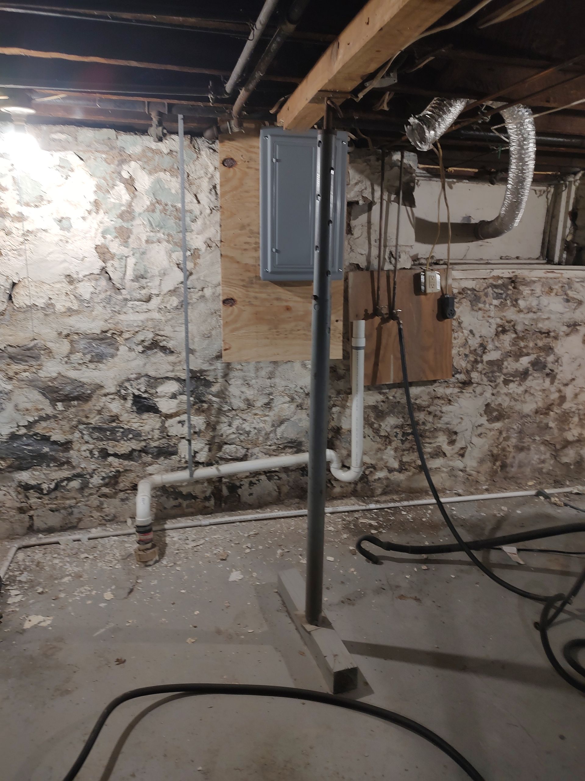 A basement with pipes and wires hanging from the ceiling.