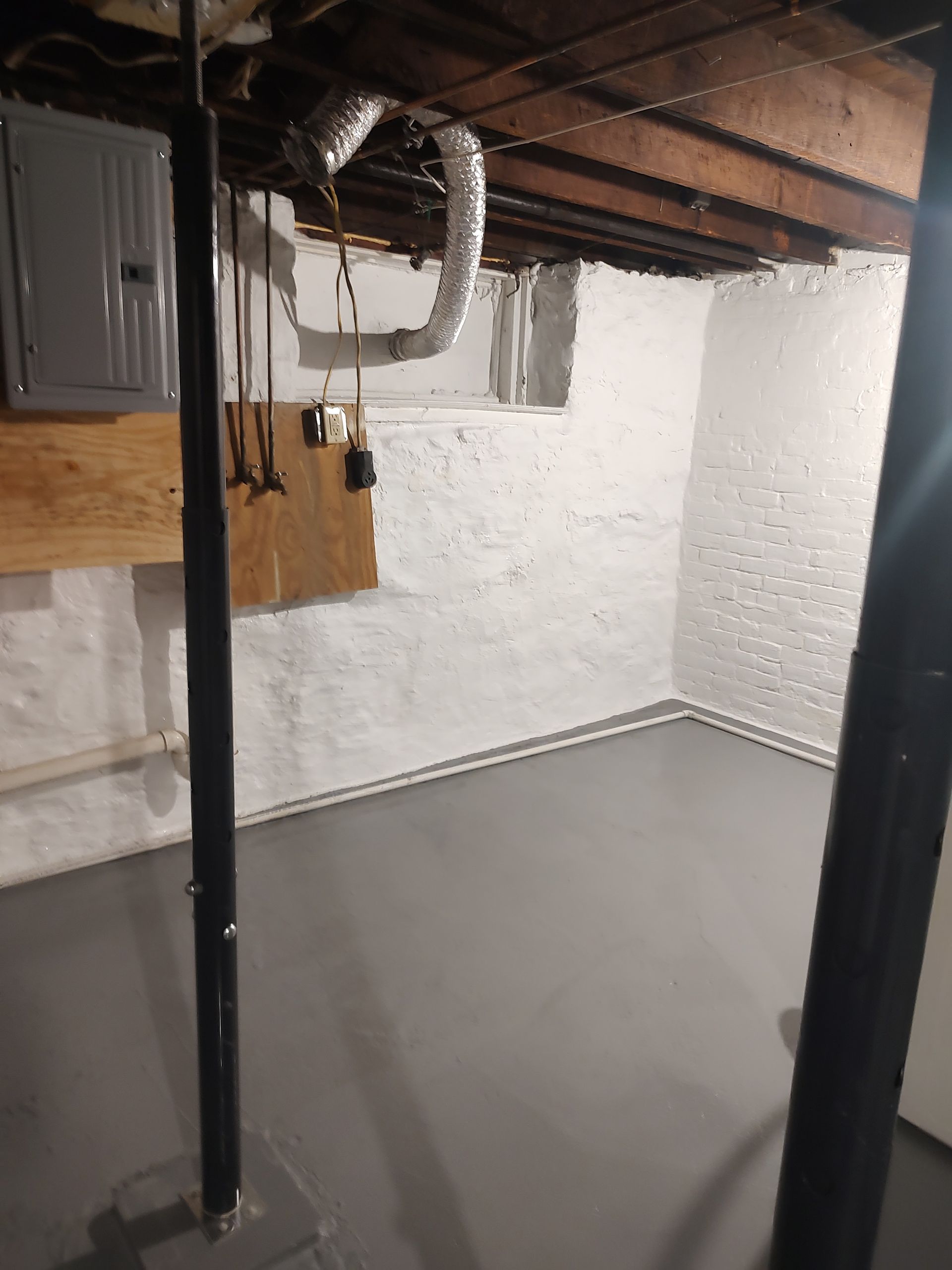 A basement with a concrete floor and a wooden ceiling.