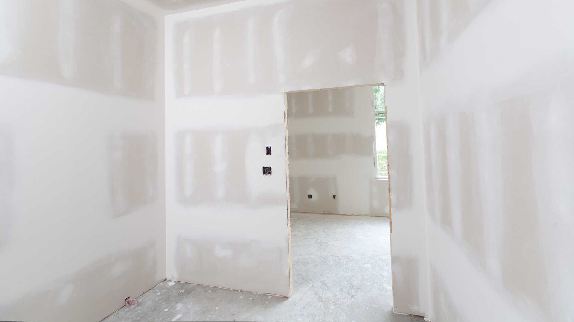 An empty room with drywall walls and a door.