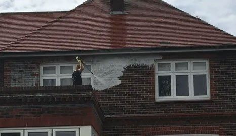 Spray washing the exterior brickwork of a house