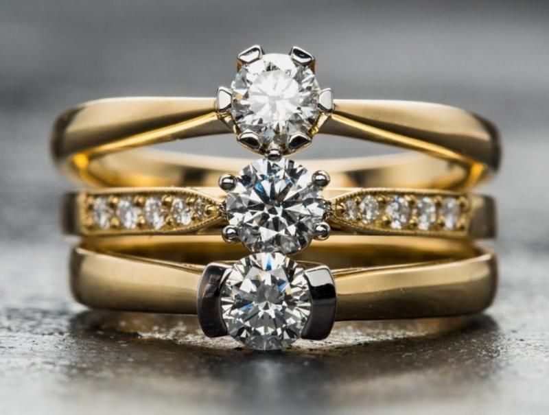 Three gold rings with diamonds stacked on a surface.