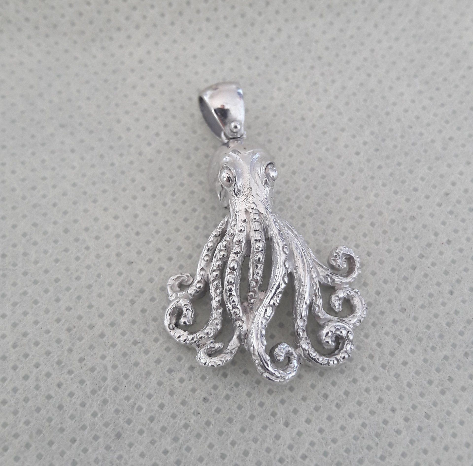 Silver octopus pendant with curly tentacles.