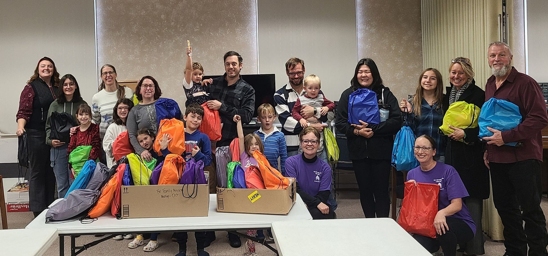 Man in purple shirt holding cookie sheets with cookies, smiling in a room with drawings on the wall.