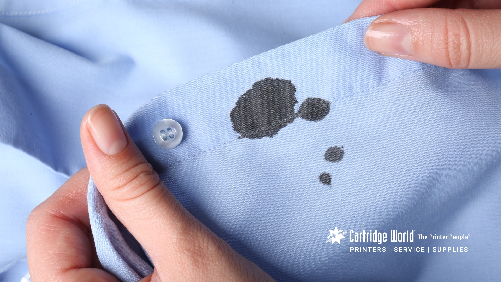 A person is holding a blue shirt with a stain on it.