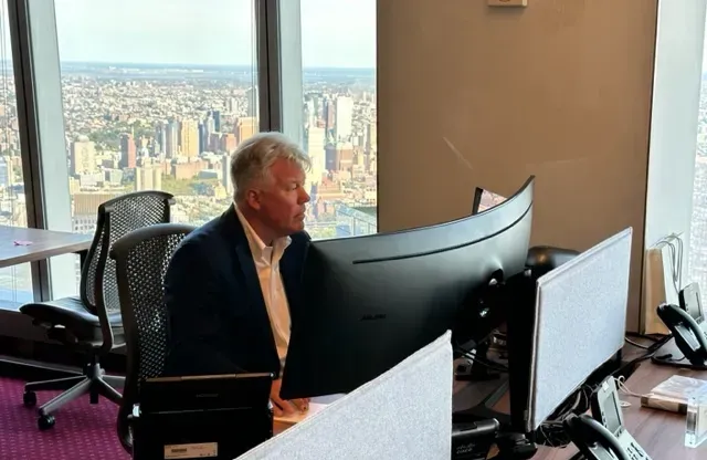 A man is sitting at a desk in front of a computer monitor.