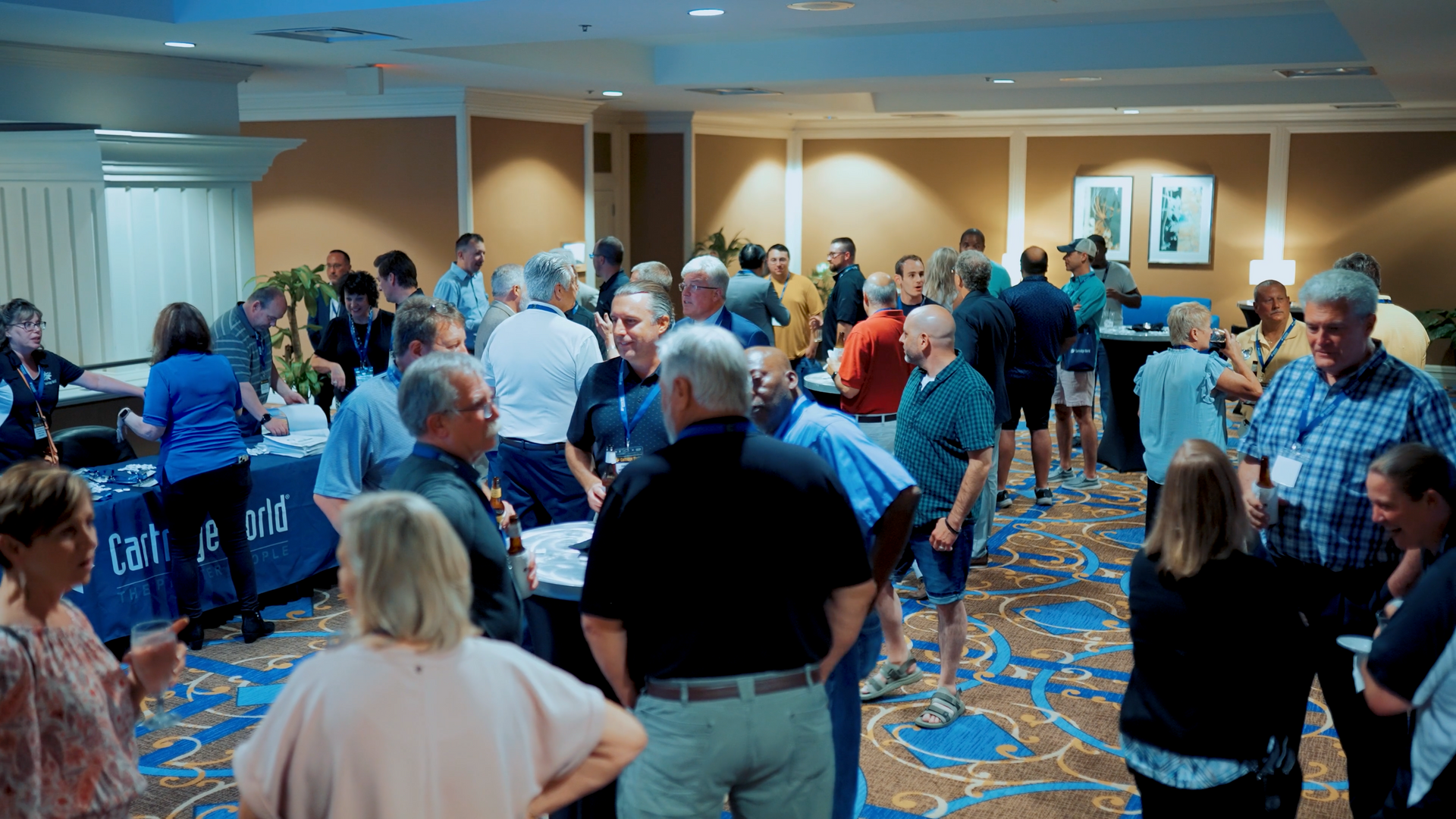 A group of people are standing in a room talking to each other.