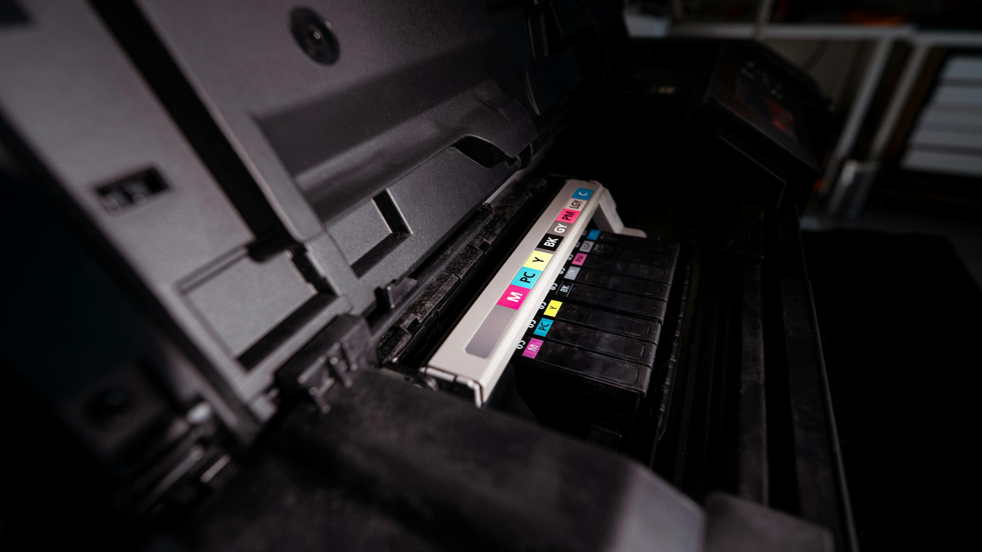 Open printer showing a row of colored ink cartridges, black interior.