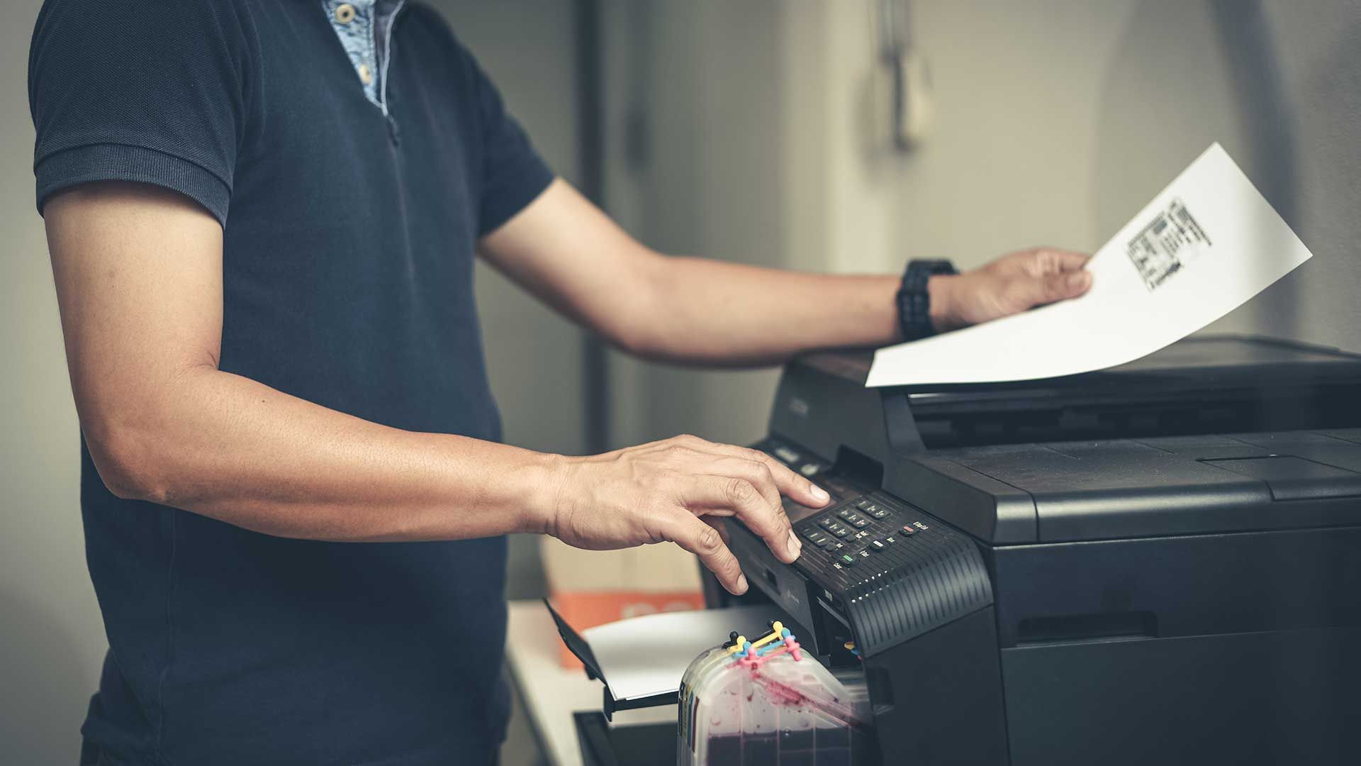 A man is using a printer to print a piece of paper.