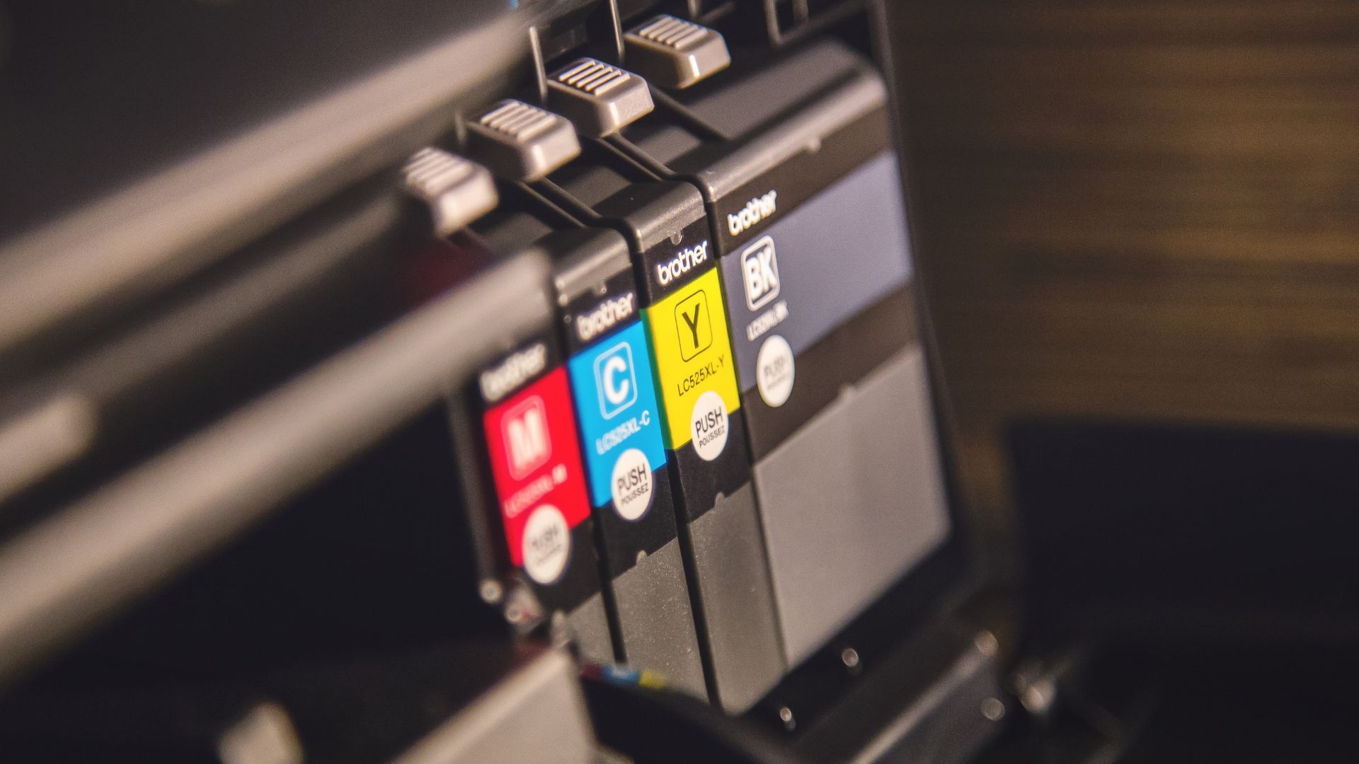 Close-up of a printer’s color ink cartridges in red, cyan, yellow, and black.