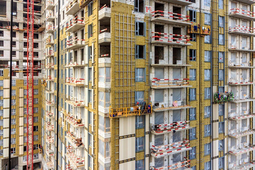 Construction cradle on wall of monolithic house under construction. Electric suspended platform is reliable for working safely at elevated height in accordance with applicable standards