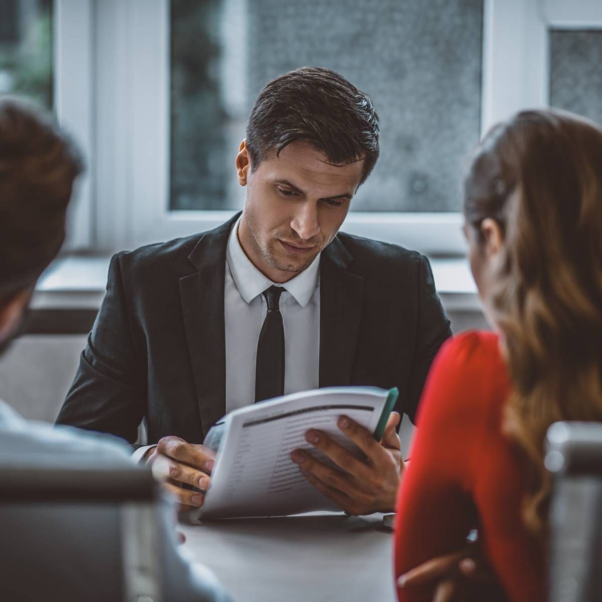 Man in suit reviewing documents with a couple seated across the table.