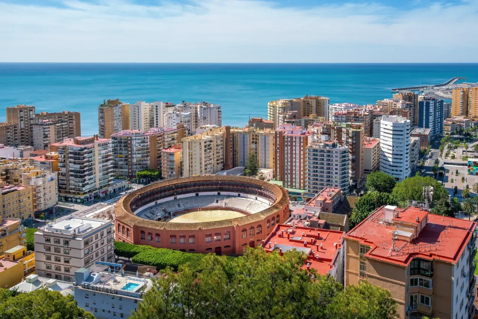 Aerial view of the Plaza de Toros de La Malagueta bullring in Málaga, Spain, surrounded by apartment blocks and the sea.