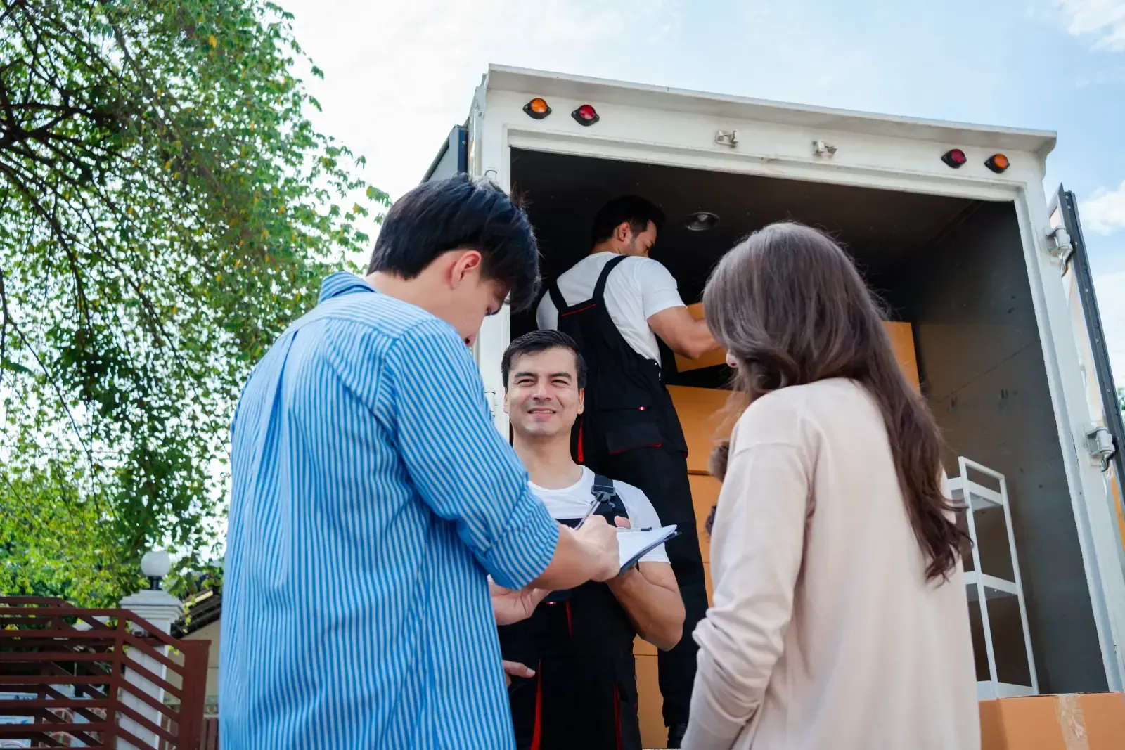 Movers loading a truck, two customers review paperwork in front of the vehicle.