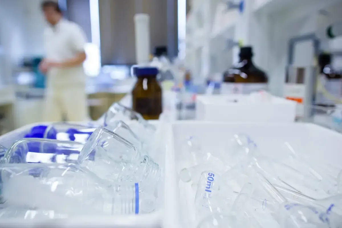 Laboratory with glassware in focus, person blurred in background.
