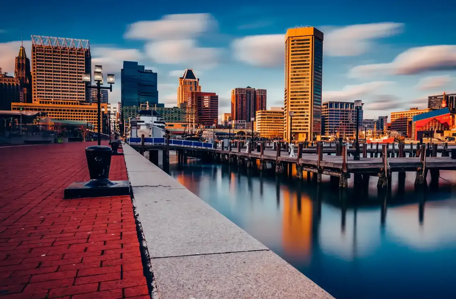 Harbor city skyline at sunset with waterfront promenade and calm canal reflections