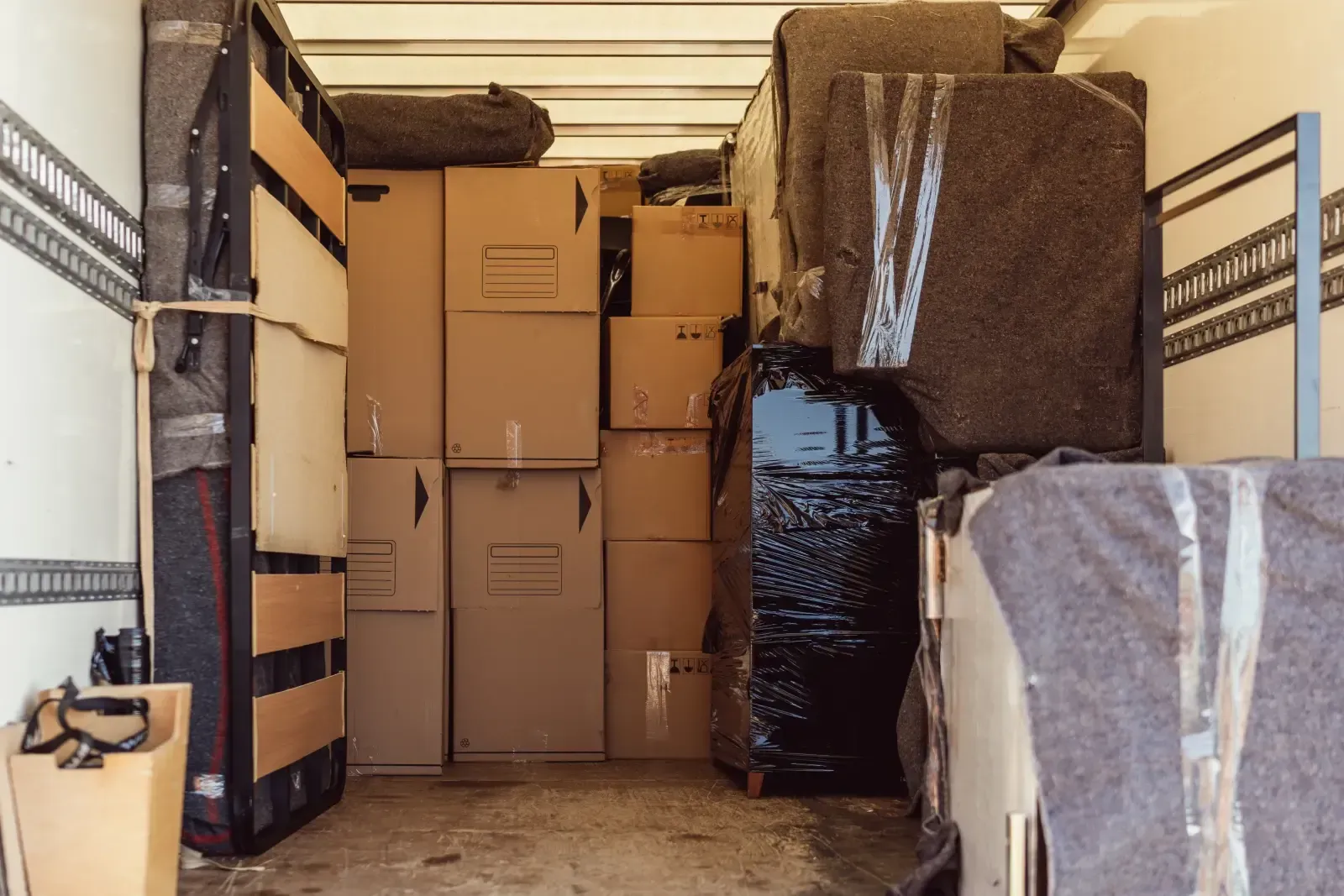 Boxes and wrapped furniture packed tightly inside a moving truck.