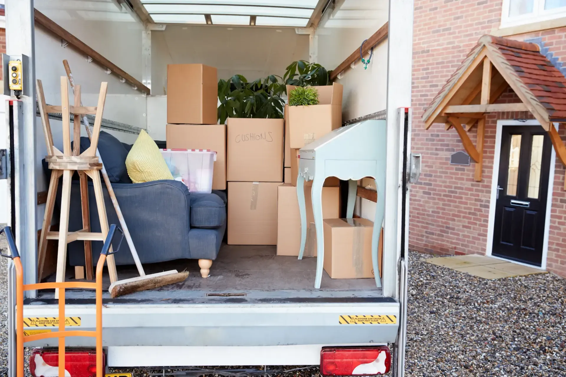 A moving truck filled with furniture and boxes is parked in front of a house.