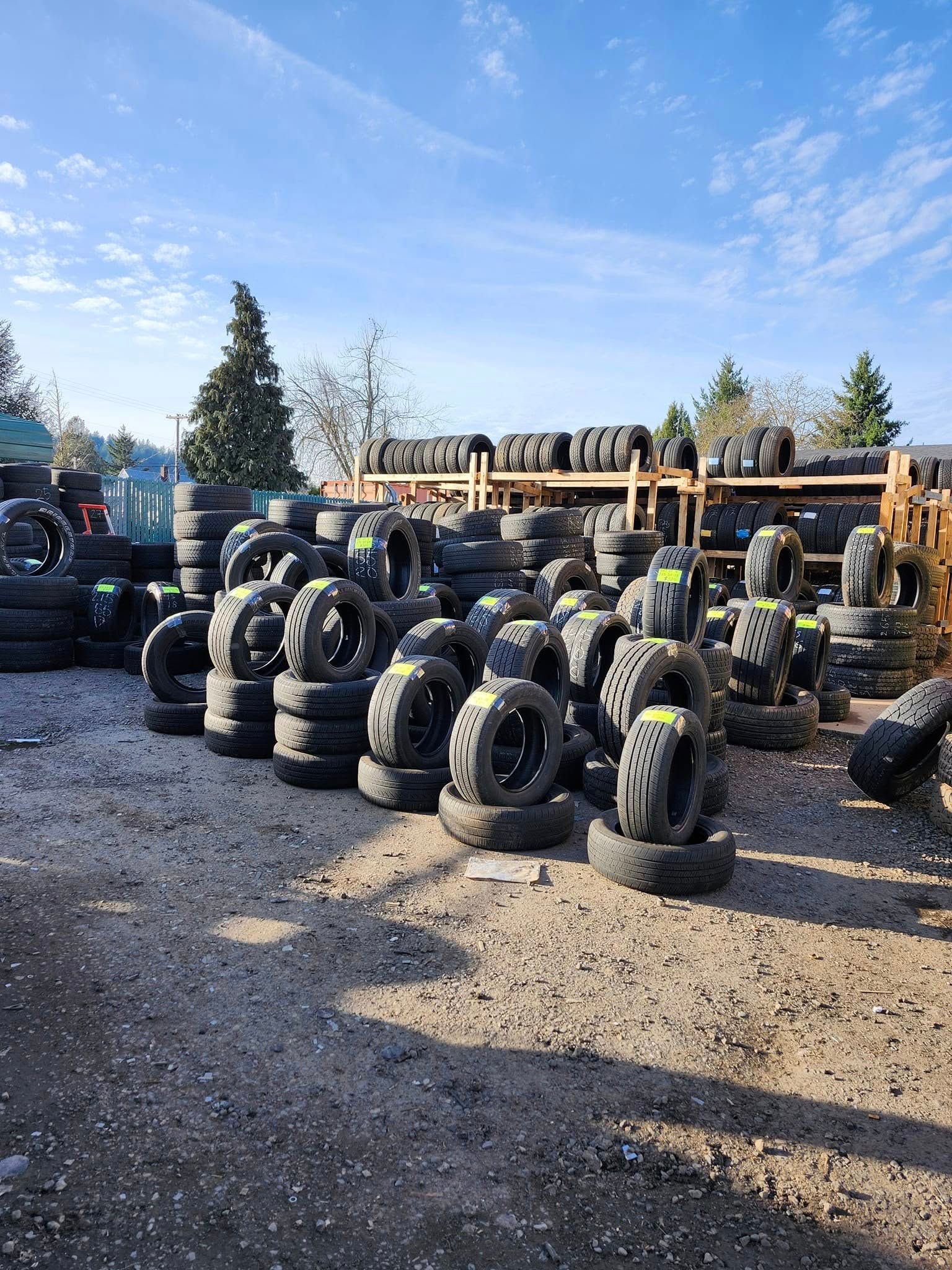 A lot of tires are stacked on top of each other in a yard.