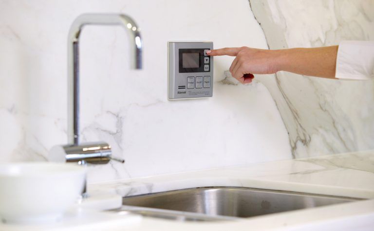 A Person is Pressing a Button on a Wall Next to a Sink — FNQ Hot Water In Mareeba, QLD
