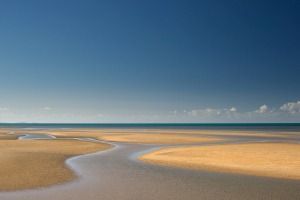 A Sandy Beach With a River Running Through It and the Ocean in the Background — FNQ Hot Water In Port Douglas, QLD