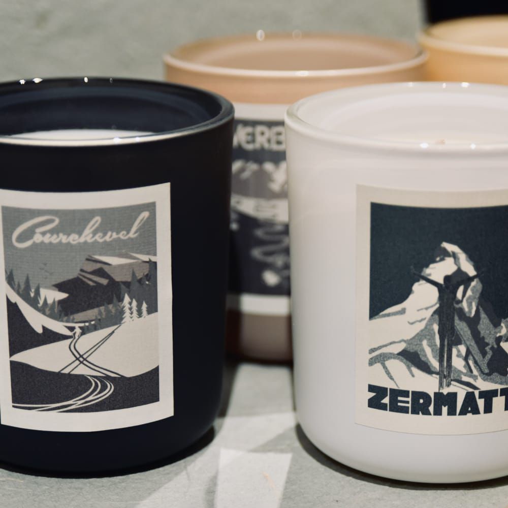 Trois bougies en verre dépoli avec des étiquettes de scènes de montagne de style vintage : Verbier, Davos et une troisième.