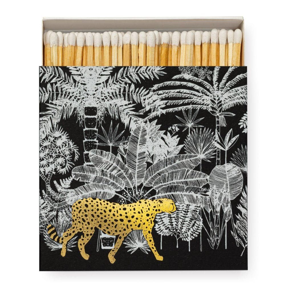 Boîte d'allumettes avec un guépard tacheté d'or marchant dans une jungle noire et blanche.