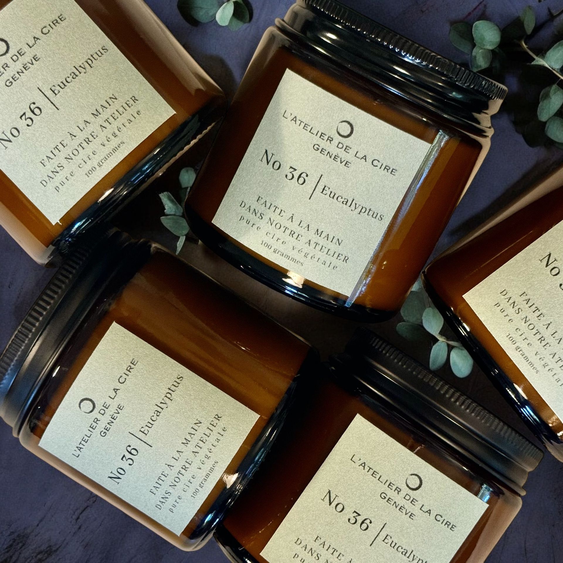 Cinq bocaux en verre avec bougies en cire brune, couvercles et étiquettes noirs. Parfum eucalyptus.