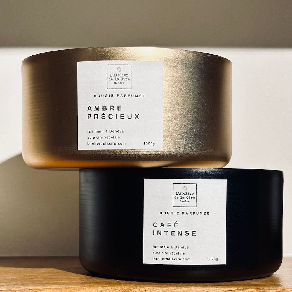 Bougie dorée, étiquette « Ambre Précieux ». En arrière-plan : des houppes ressemblant à de la barbe à papa.