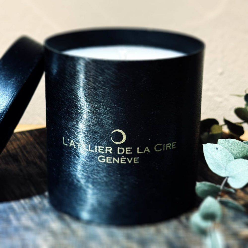 Bougie noire dans un contenant cylindrique avec le logo