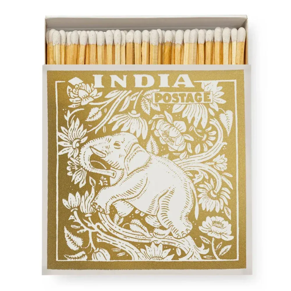 Boîte d'allumettes avec motif floral et éléphant doré, étiquetée « INDIA POSTAGE ».