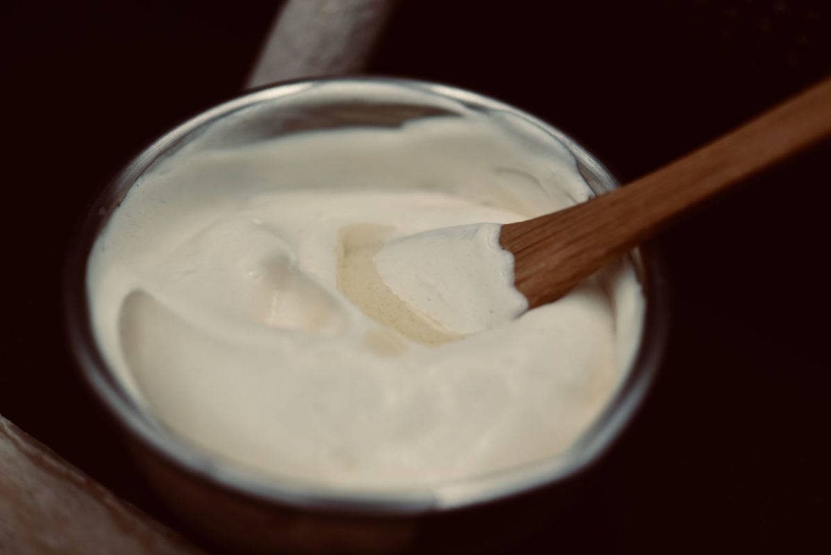 Bowl of white cream with wooden spoon.
