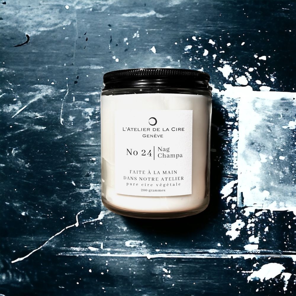 Un pot à bougie sur une surface bleu foncé, avec des éclaboussures blanches. L'étiquette indique « N° 24 » et « Nuit Champêtre ».
