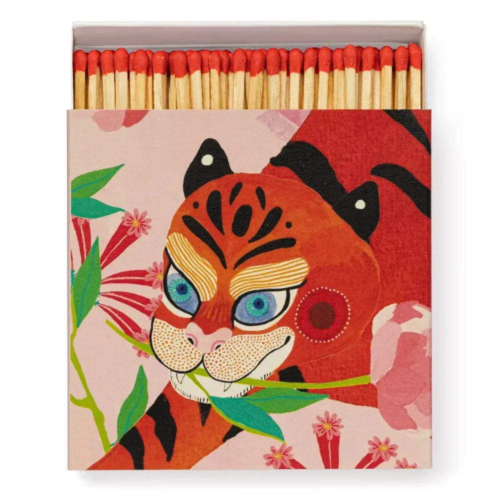 Boîte d'allumettes avec une illustration de tigre rouge stylisé sur fond rose.