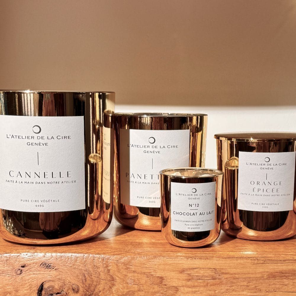 Cinq bougies dorées avec des étiquettes blanches sur une surface en bois.