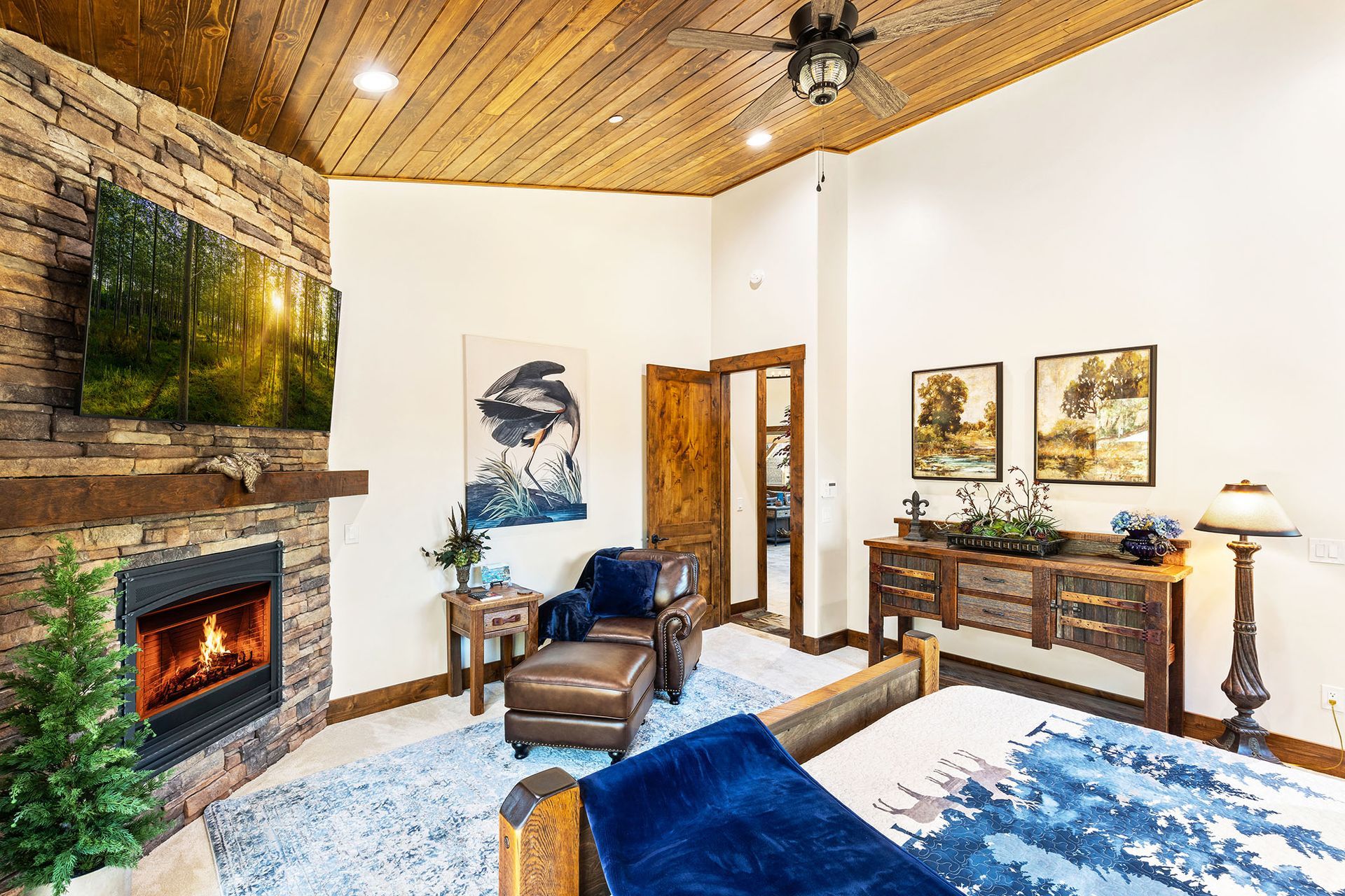 A bedroom with a bed , fireplace , chairs and a television.