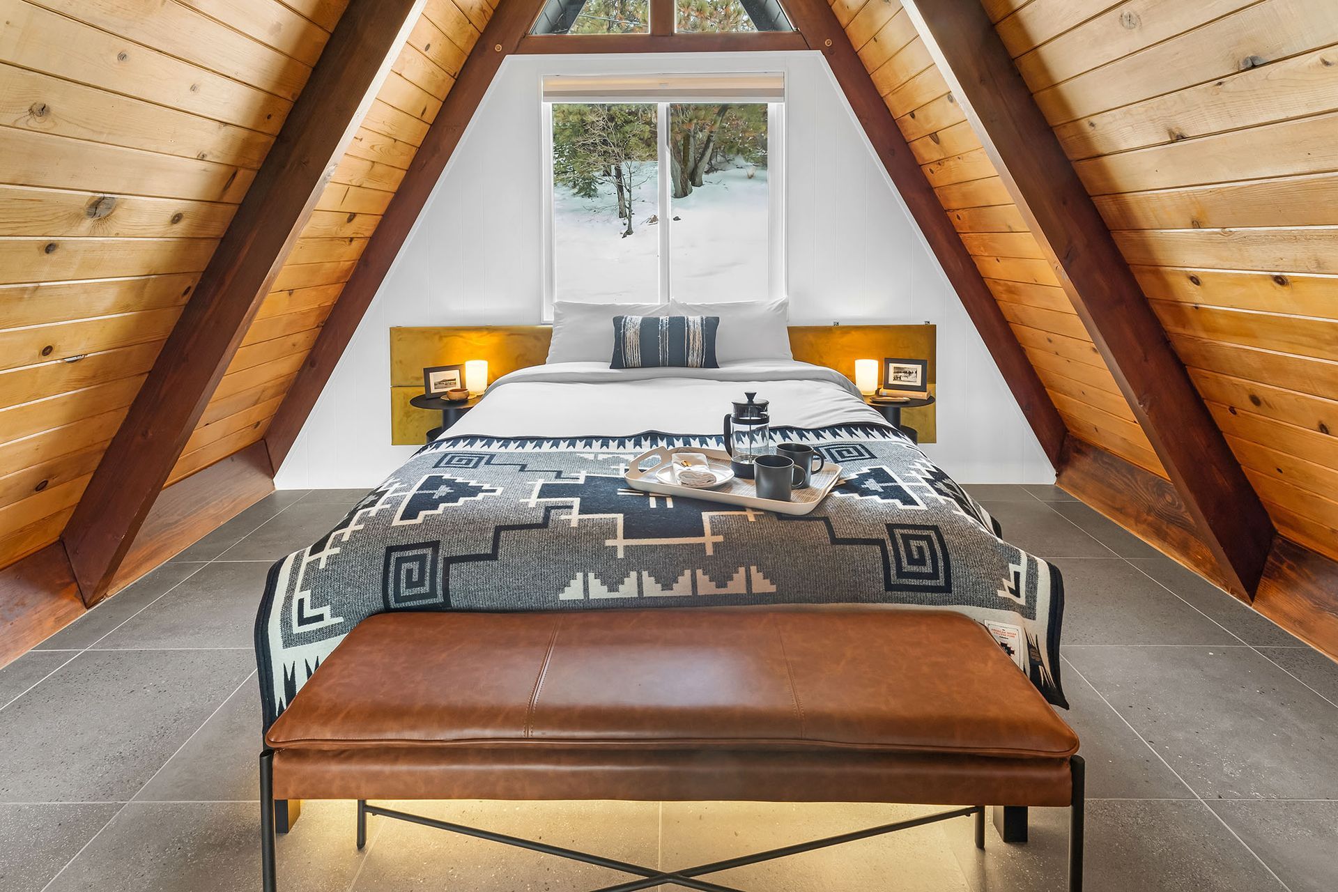 A bedroom with a bed and a bench in the attic.