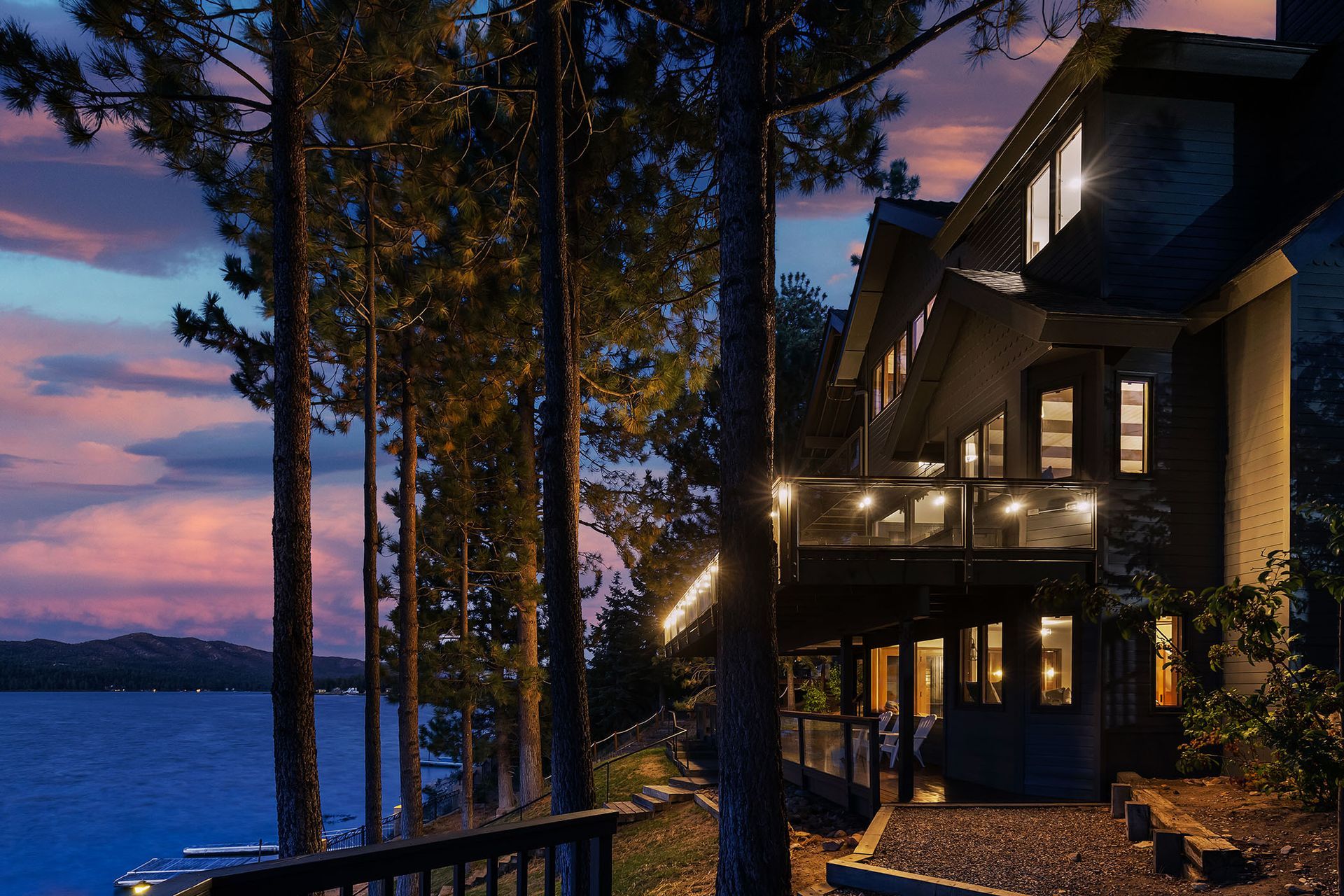 A large house sits on the shore of a lake at night.