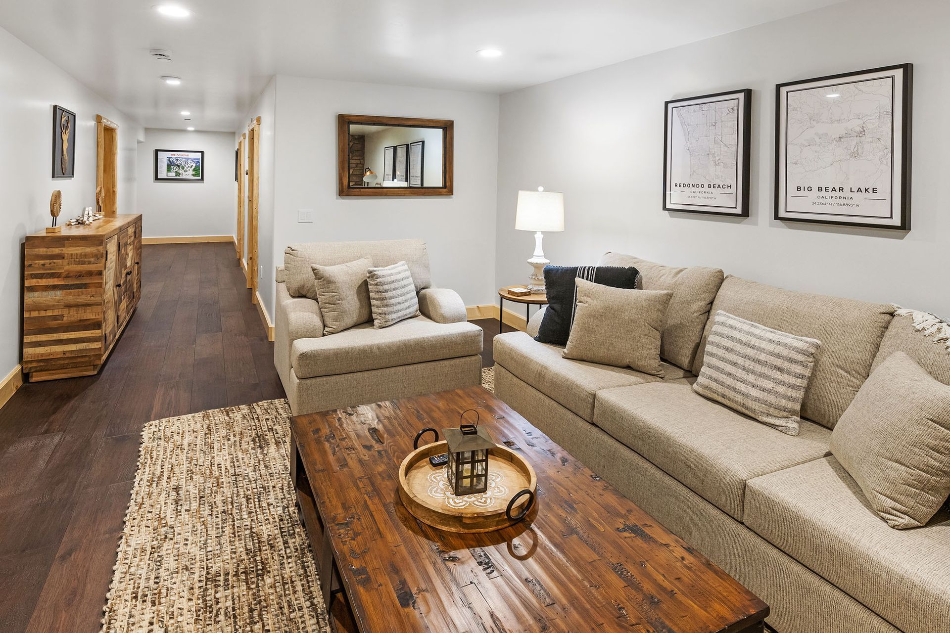 A living room with a couch , chair , coffee table and mirror.