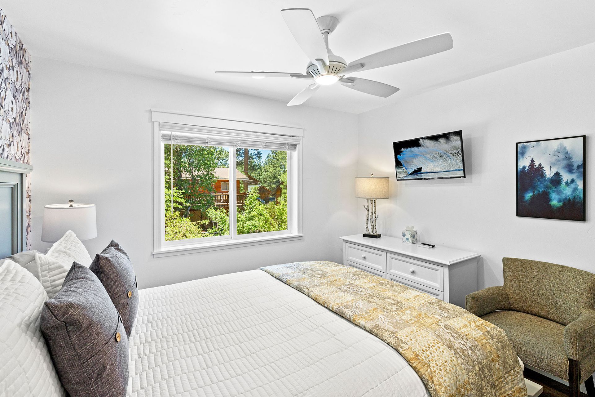 A bedroom with a bed , chair , dresser and ceiling fan.