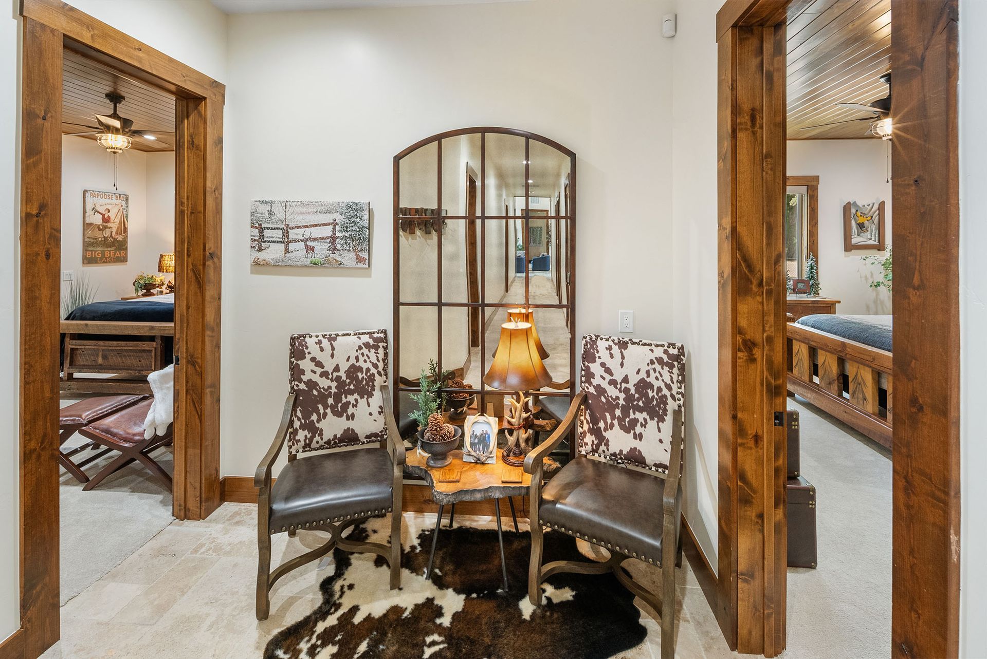 A living room with two chairs , a table and a mirror.