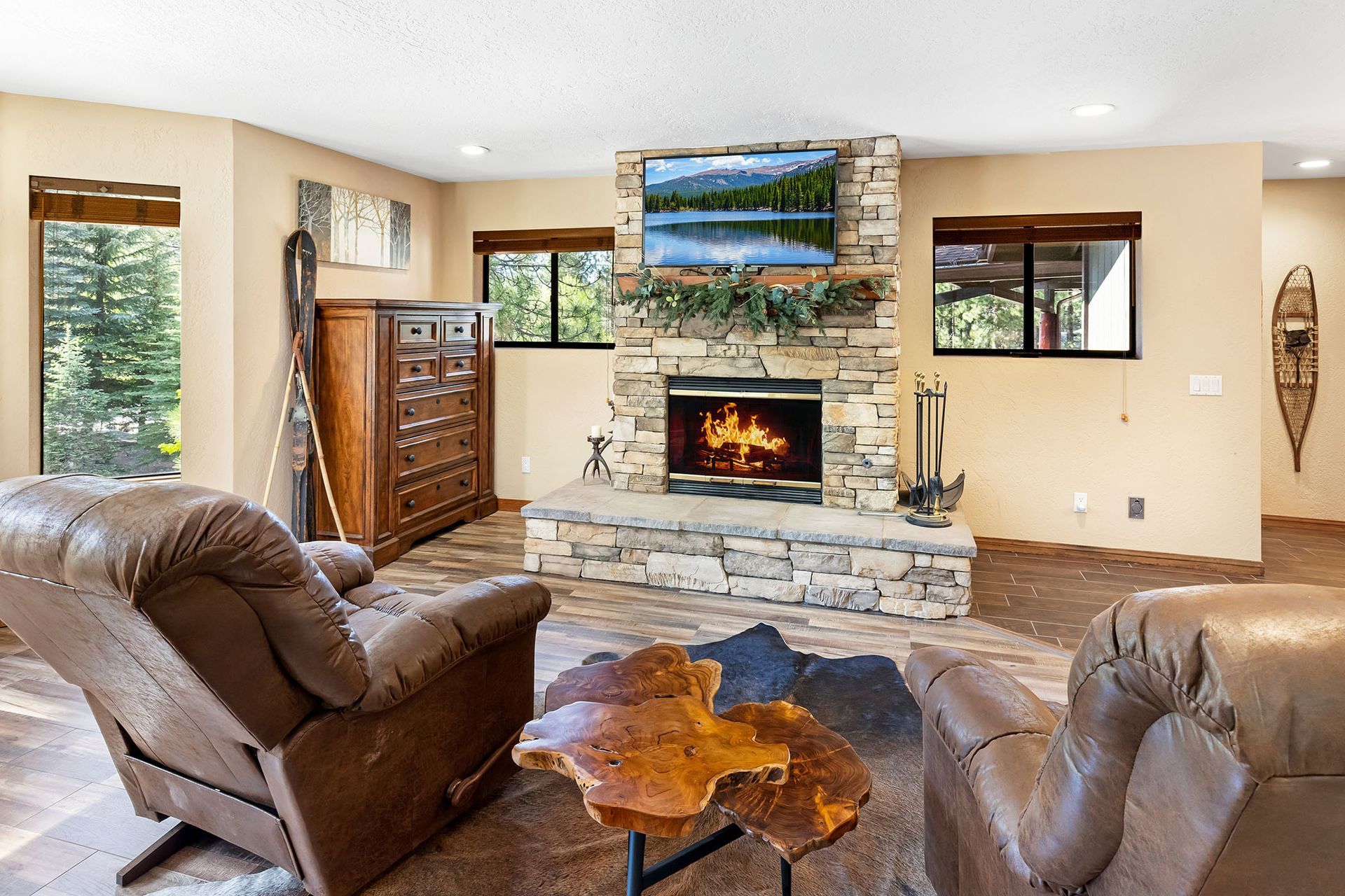 A living room with a fireplace , two chairs , a table and a television.