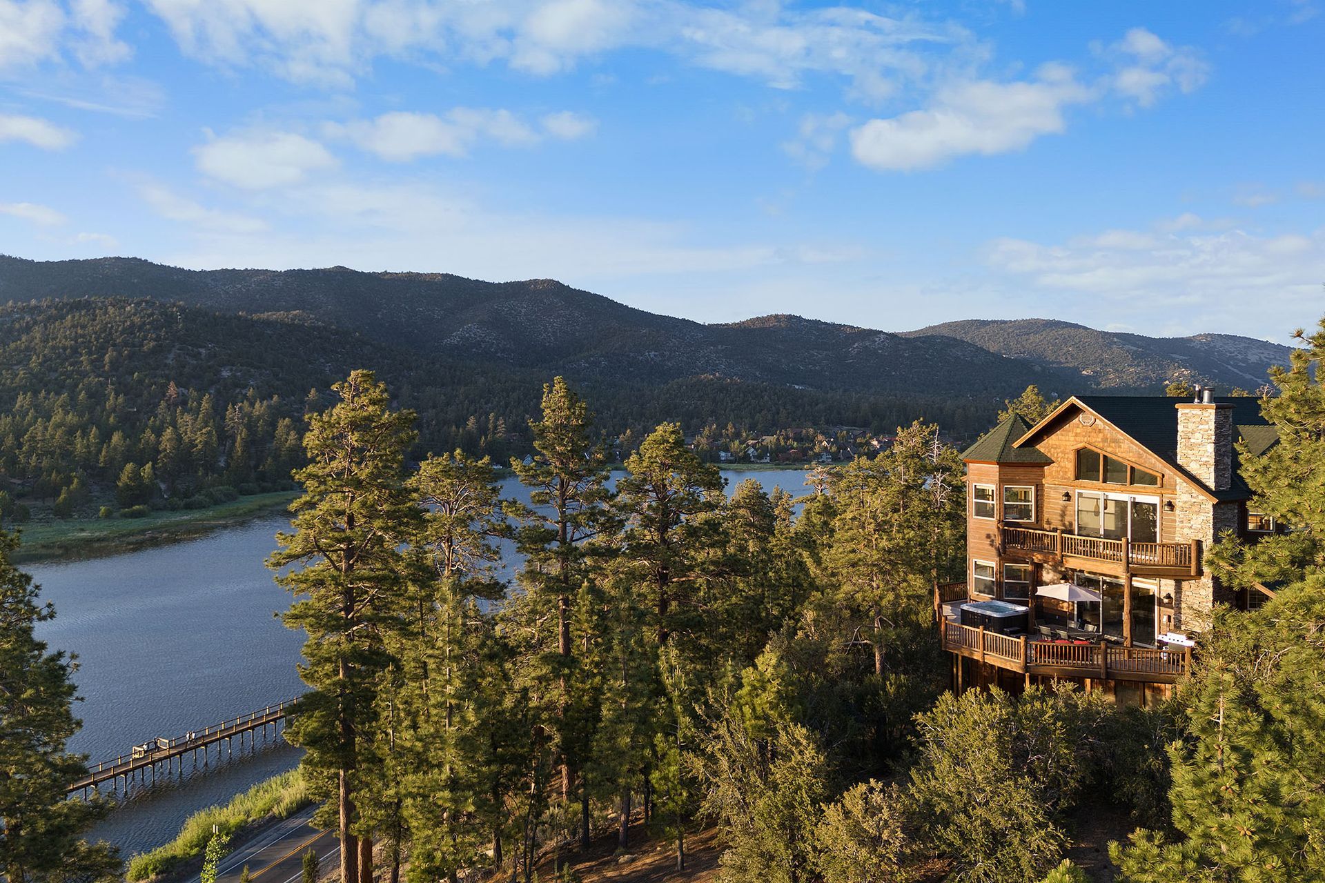 An aerial view of a house surrounded by trees next to a lake