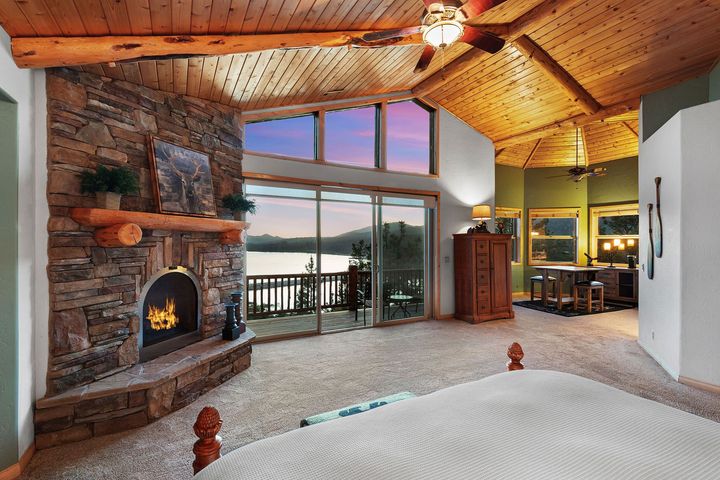 A bedroom with a fireplace and a view of a lake