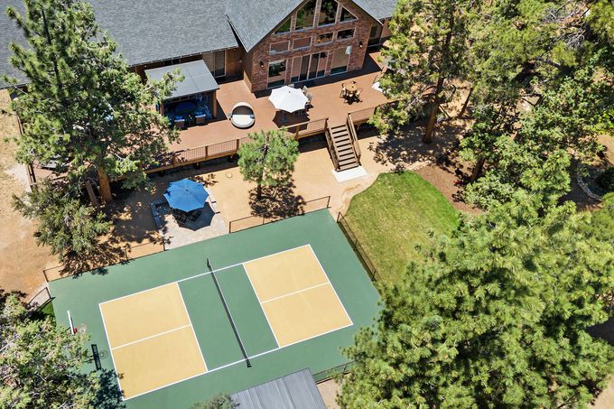 An aerial view of a tennis court in front of a house