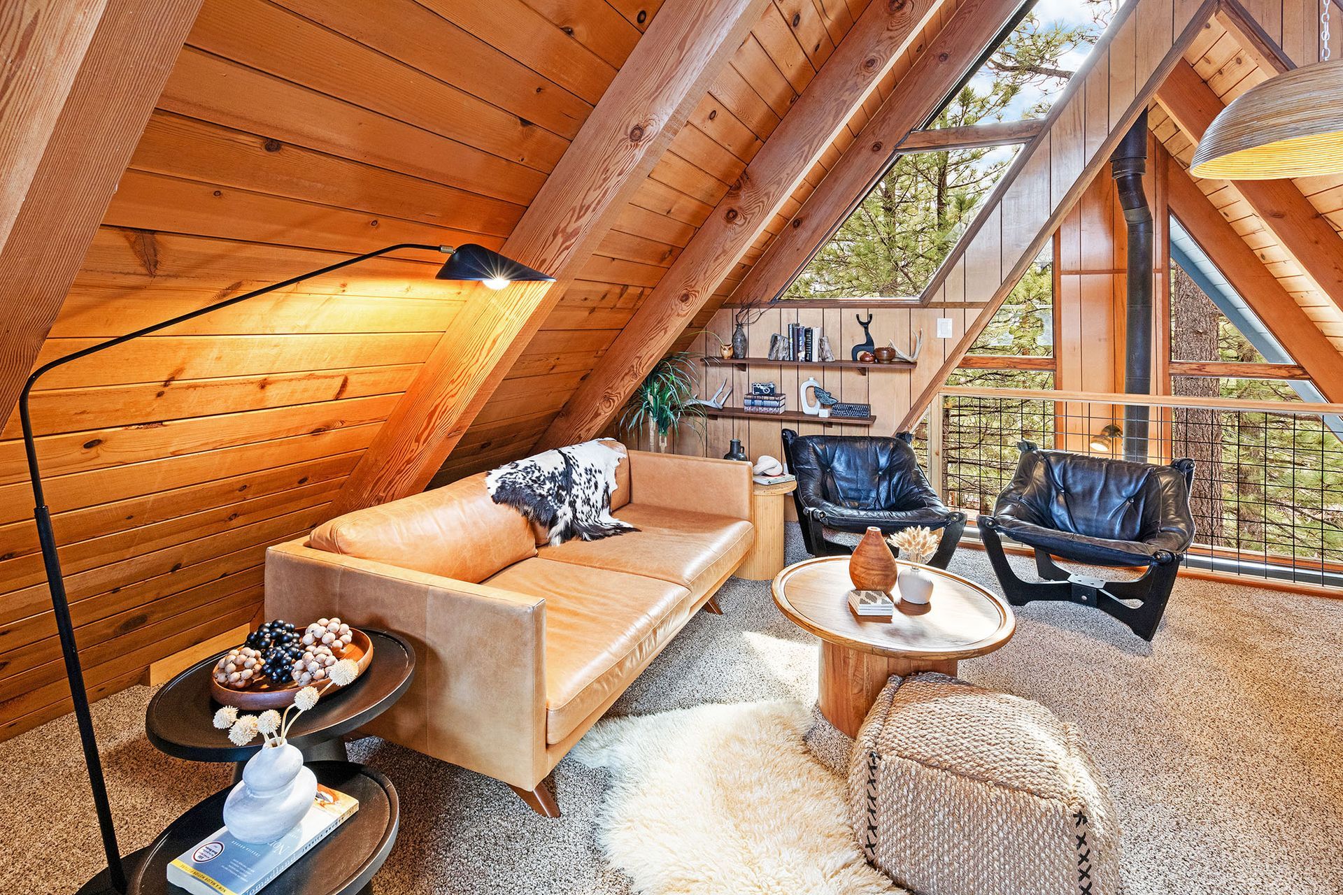 A living room with a couch , chairs , tables and a lamp.