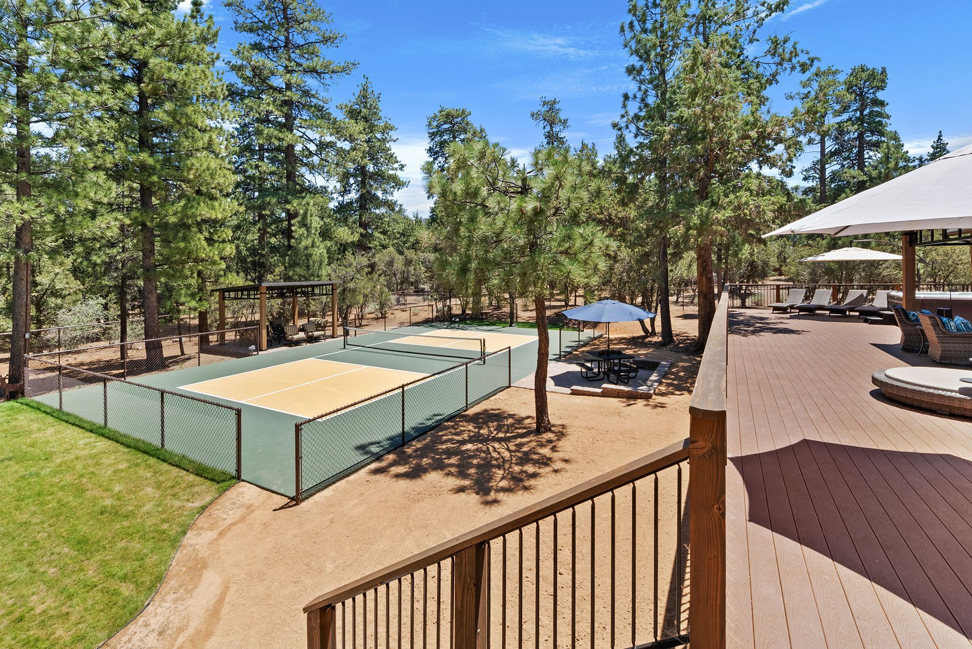 A view of a volleyball court from a deck surrounded by trees.