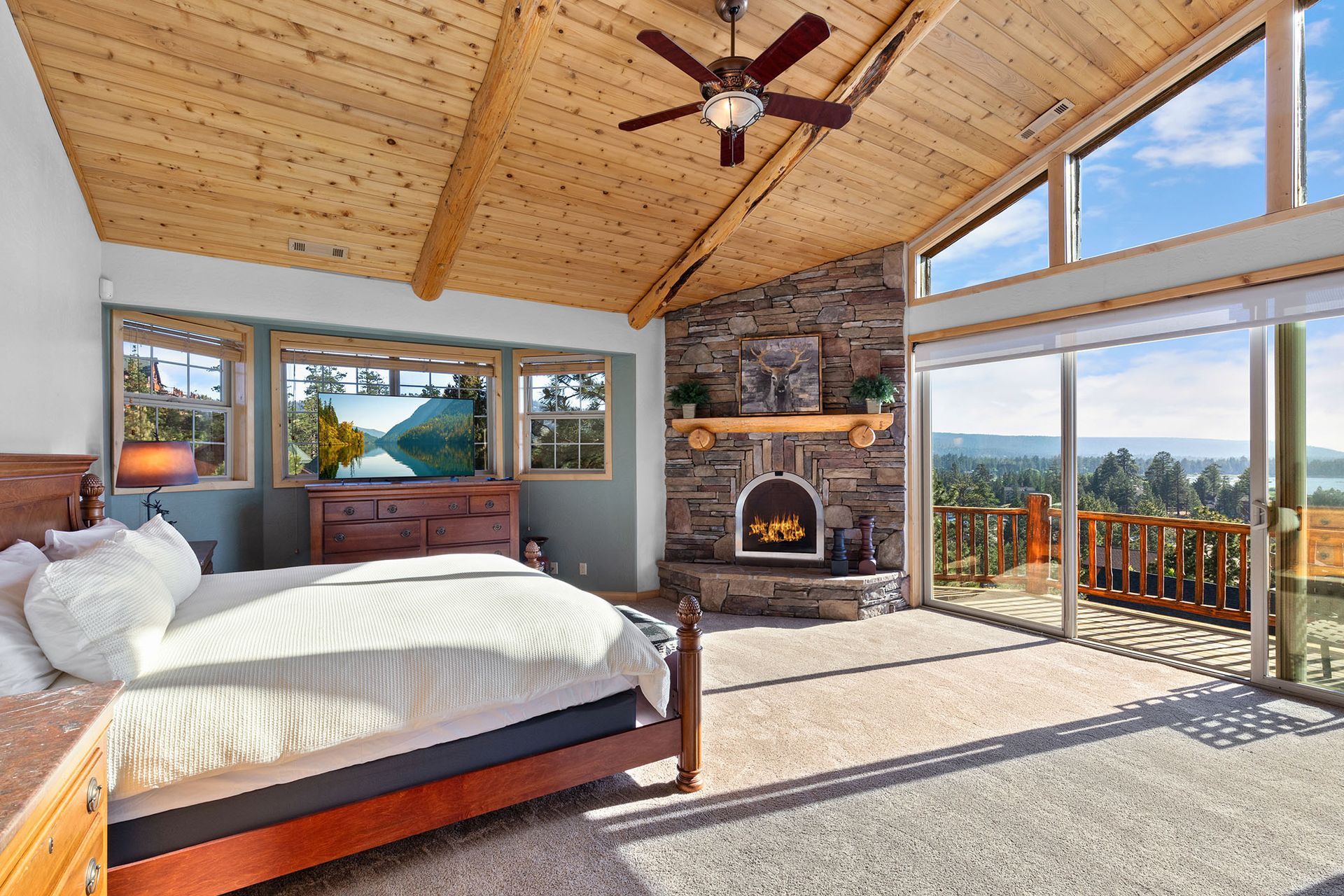 A bedroom with a large bed , fireplace and sliding glass doors.