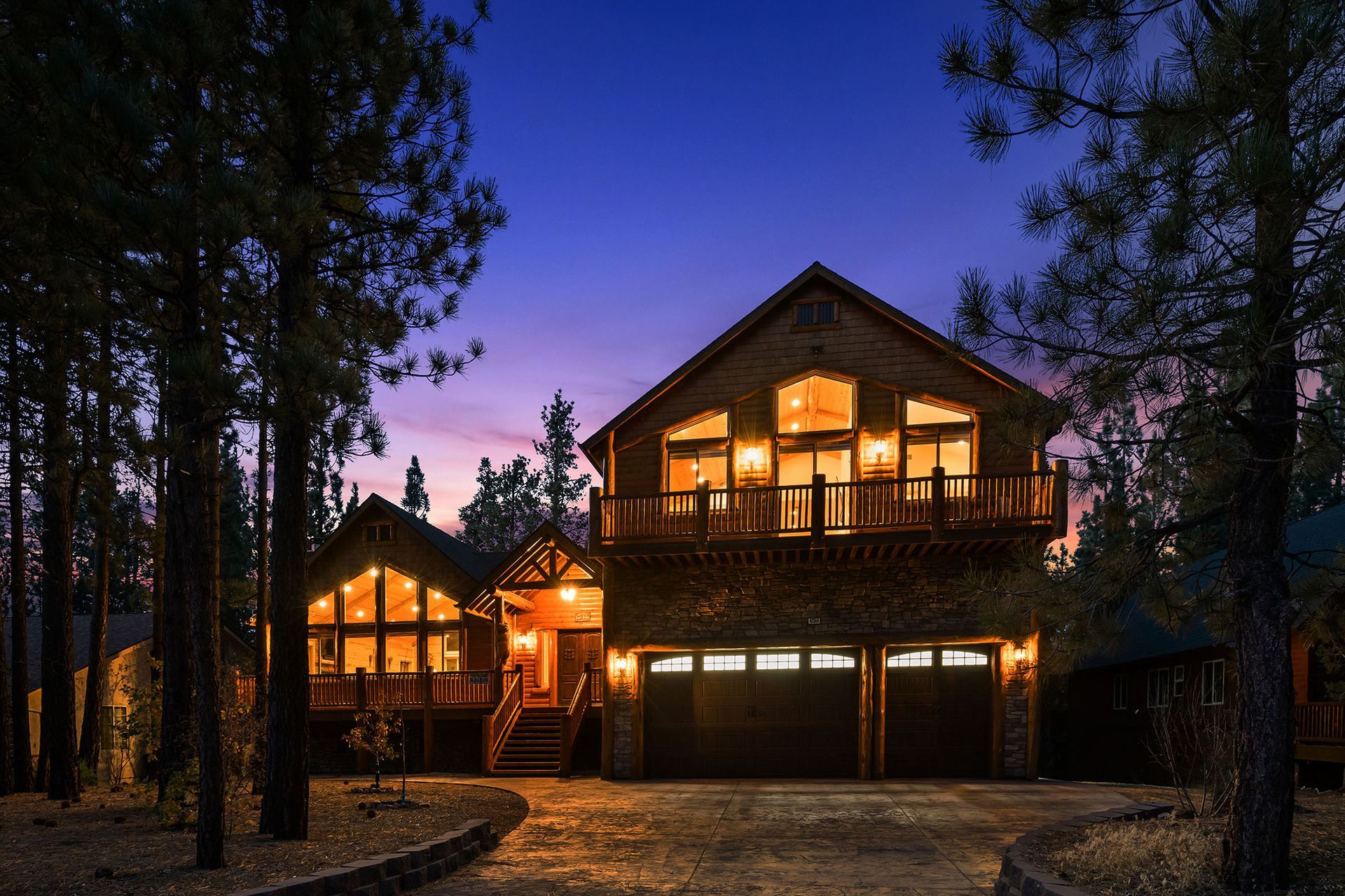 A large house is lit up at night in the woods
