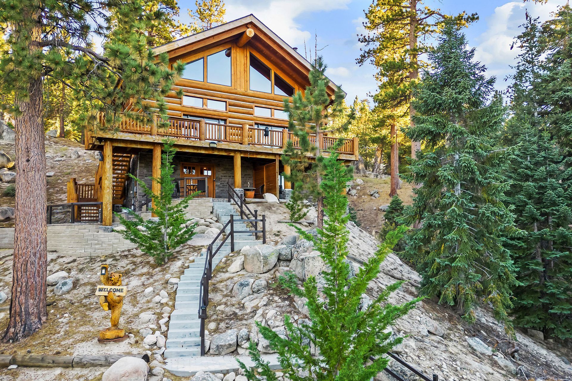 A large log cabin is sitting on top of a hill in the middle of a forest.