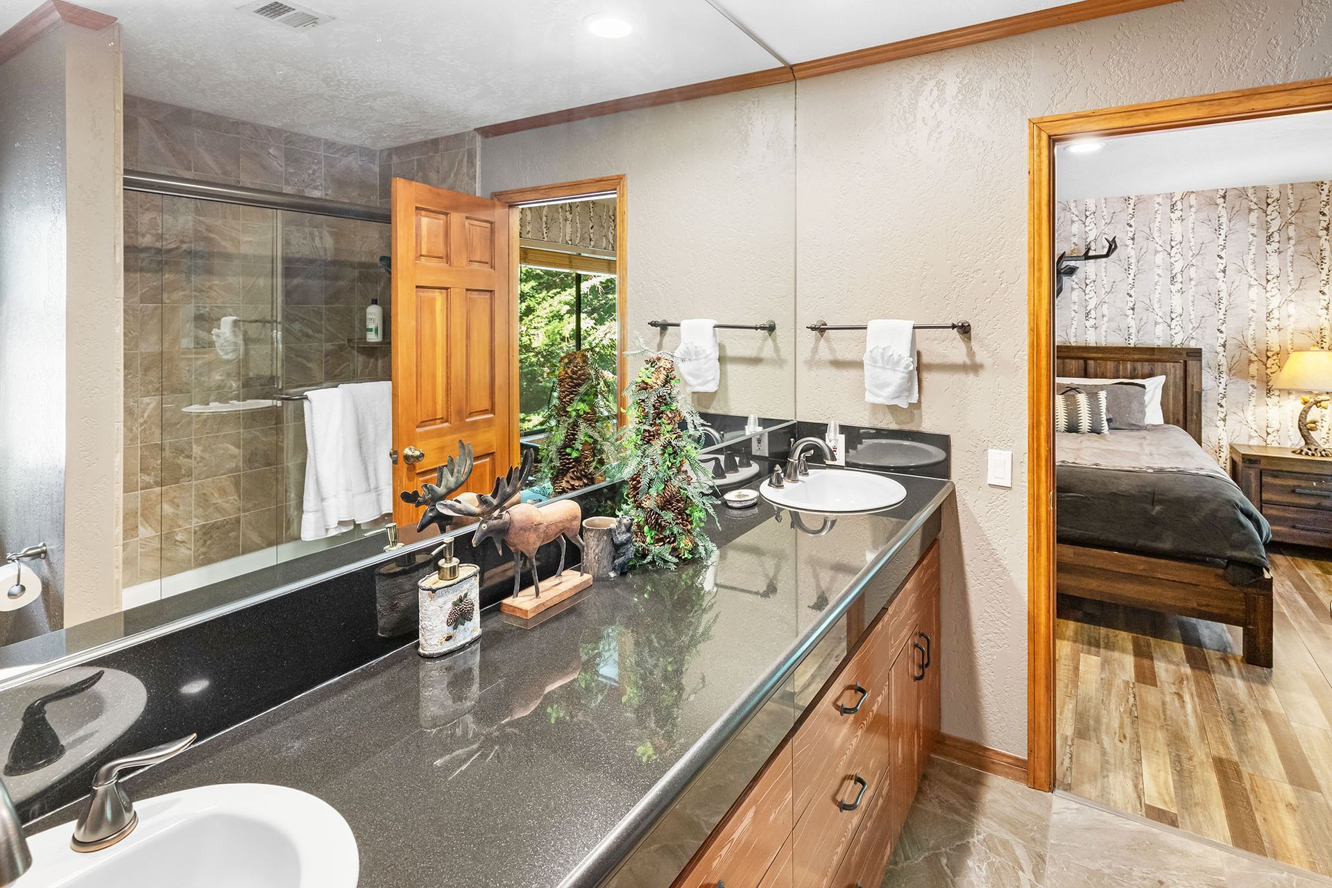A bathroom with two sinks , a large mirror and a walk in shower.